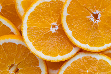 Freshly cut oranges sliced in round pieces arranged on a flat surface in bright yellow color during daylight hours