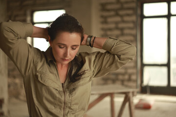 Woman in overalls stands in middle of room construction worker