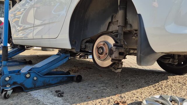 Tire service. A car lifted with a jack for seasonal tire changes.