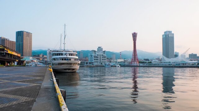 Kobe, Japan. View of sunrise in Kobe, Japan. A cloudless sky with harbor and numerous skyscrapers and Port Tower. Time-lapse
