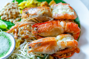 Prawn Pad Thai, close-up. Pad Thai with grilled river prawns, stir fried noodles in rich sauce served with fresh vegetables. Authentic Thai cuisine, ideal for food, restaurant, and travel content