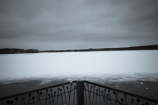 Winter view of a frozen reservoir with a cloudy sky, a fence in the foreground, hiking in snow and icy temperatures around the Th&uuml;lsfeld reservoir, Cloppenburg, Lower Saxony, Germany