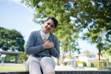 Obraz premium Elderly woman holding chest feeling discomfort outdoors