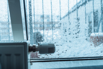 Heating radiator thermostat, window covered with snow in winter weather