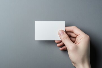 Obraz premium Hand holding blank business card on gray background for personalized branding and business communication needs