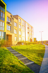 Fototapeta premium Steps stairs on pedestrian path to entrance of residential building. Eco-friendly condominium with green courtyard. Lawn at Condo house complex. Entrance to apartment block. Entrance facade building.