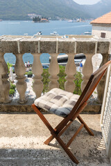 Naklejka premium A wooden folding chair with a plaid cushion sits on a stone balcony