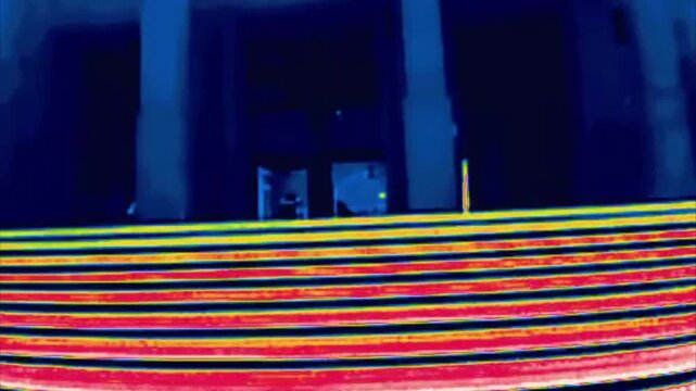 Children play on the wide front staircase of a government building with columns. Image from thermal imager device.