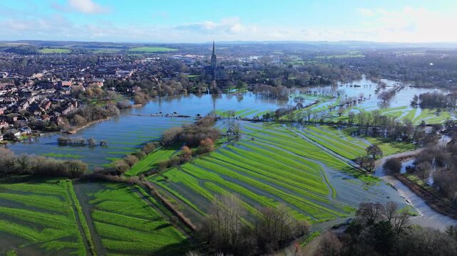 Tracking aerial shot of flooded meadows and Salisbury cathedral after Storm Chandra