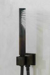 The black shower head is spraying water.