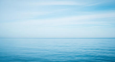Obraz premium Serene ocean landscape with calm waters under soft blue sky