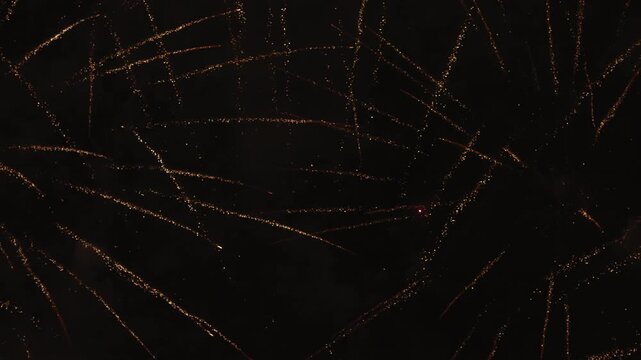 Dazzling display of golden fireworks exploding in the dark night sky. This festive pyrotechnic sequence builds in intensity, filling the screen with sparkling trails. Perfect for celebrations.
