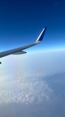 Obraz premium Airplane Wing View Above Clouds with Clear Blue Sky During Flight