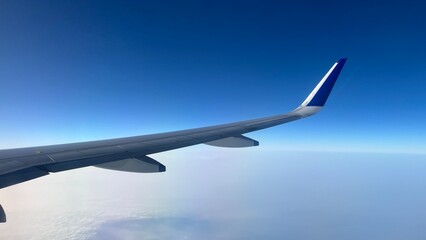 Airplane Wing View Above Clouds with Clear Blue Sky During Flight