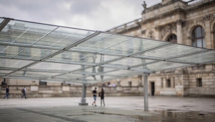 Obraz premium Cloudy day at a museum courtyard with solar canopy in clear view panels sharply detailed while the softly blurred historical architecture fades behind.