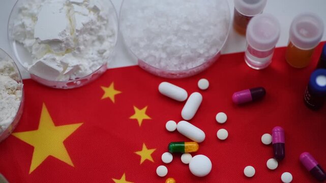 A top view, macro pan clip of medicine substances, liquids, and various loose and packaged medicine on the flag of China. A China pharmaceuticals and medicine science concept.