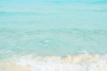 Obraz premium A sandy beach with clear turquoise water and small waves washing up on the shore