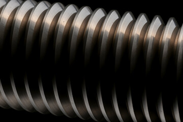 Detailed close-up of a threaded metal rod against a dark background, showcasing precision engineering and industrial texture.