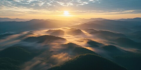 A breathtaking aerial view of a mountain range at sunrise, with a thick layer of fog and mist covering the valleys and peaks. 