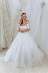 Fototapeta premium Beautiful girl in a white long luxurious wedding dress. Model bride posing in a gentle location