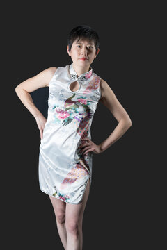 Chinese woman in white traditional dress leans to her left with hands on hips