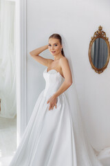 Fototapeta premium Portrait of a bride in a white lush luxury dress with pearls. Dress fitting before the wedding