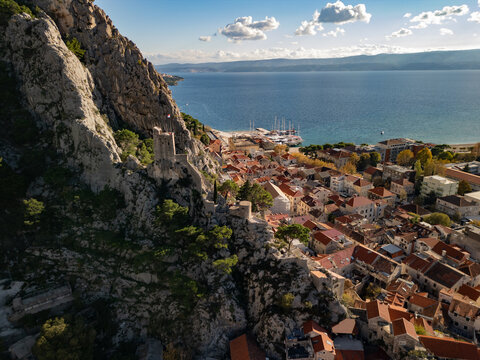 Horizontal aerial view of the historic Mirabella Fortress (Peovica) on a rock. Old town with red roofs and Adriatic sea in Omis, Croatia.