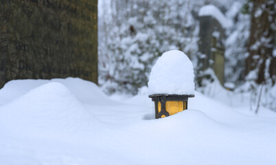 Winterwetter mit reichlich Schnee auf Ästen im Park auf Friedhof mit Grablicht im Schnee