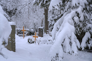 Winterwetter mit reichlich Schnee auf Ästen im Park auf Friedhof
