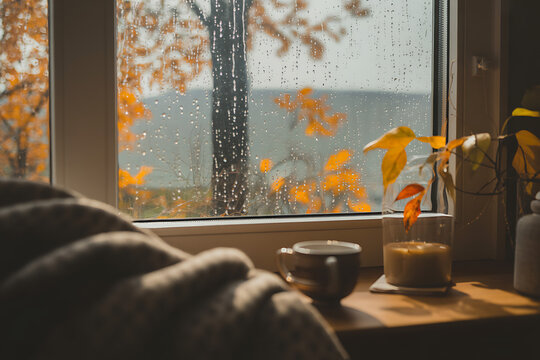 Cozy autumn morning by rainy window with warm candlelight