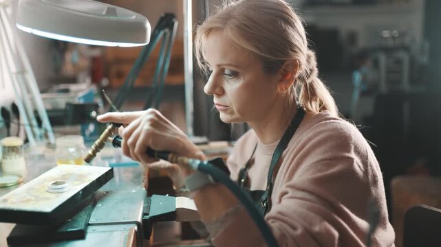Female jeweler using a gas torch for soldering