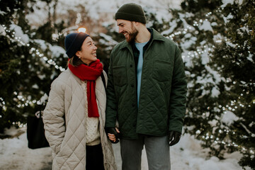 Naklejka premium Couple enjoying a winter stroll amidst twinkling lights in a snowy park