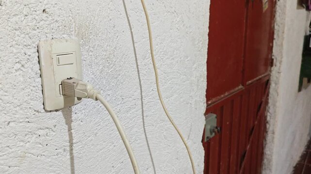 Hand of a person plugging a power cord into an electrical wall outlet