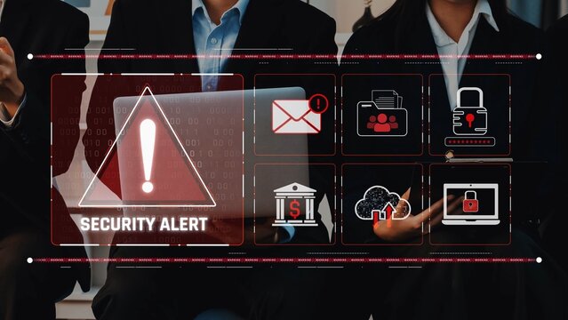 A professional business team collaborates in a modern office, focusing on a cybersecurity alert displayed on a digital dashboard, signaling the importance of data protection. Raster