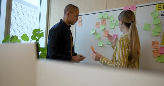 Collaborative Planning on Whiteboard with sticky notes between Two Business People