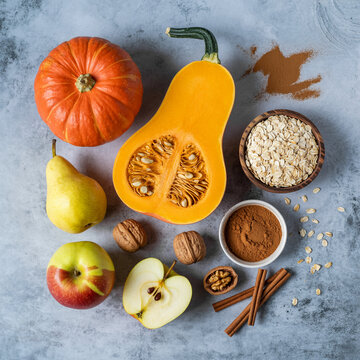 Overhead view of autumn harvest ingredients including pumpkins pears apples walnuts cinnamon and oats