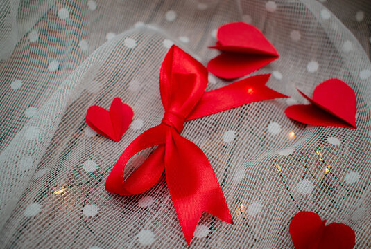 Mo&ntilde;o color rojo con liston rojo en fondo de macera con luces y corazones de papel