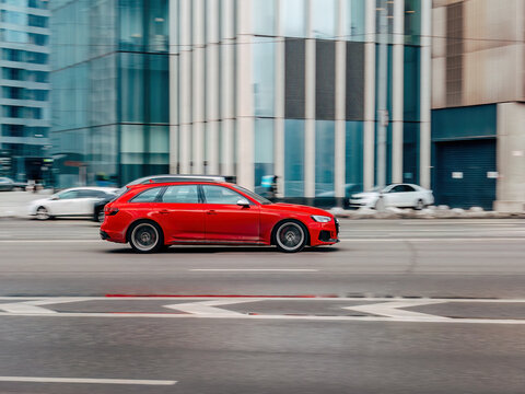 bright red Audi RS4 Avant is in motion, driving along a city street