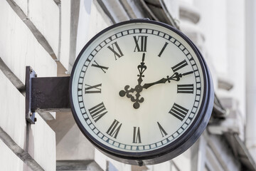 a clock on the wall of a building showing twelve o'clock, twelve minutes past