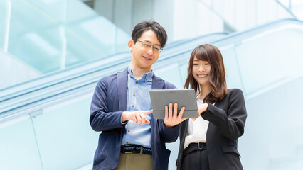 タブレットで確認する男女2人のビジネスチーム, Business team checking data on a tablet outdoor © Trickster*
