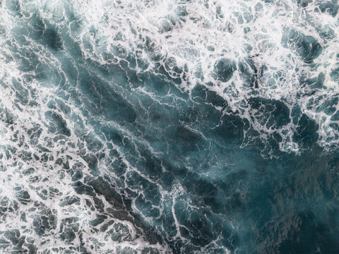 Aerial view of deep turquoise waters churn with frothy white waves, creating a mesmerizing dance of light and shadow, Moya, Gran Canaria, Canary Islands, Spain.