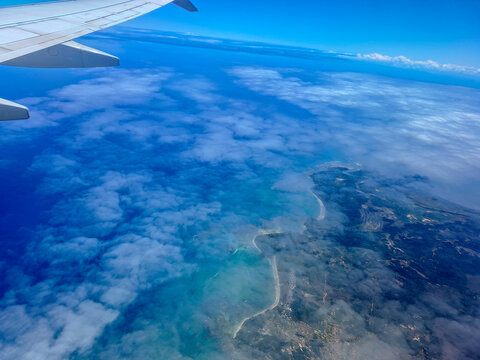Airplane Wing Over Coastline and Blue Ocean