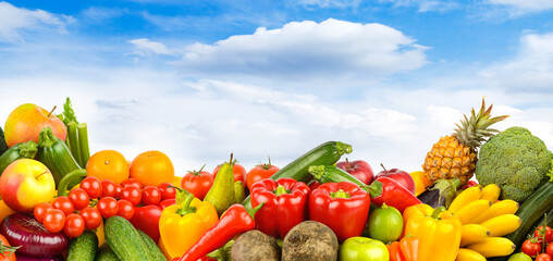 Vibrant fruit and vegetable mix displayed in open-air setting with bright sky background