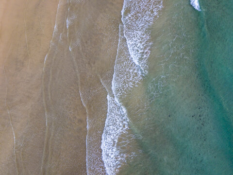 Aerial view of golden sand meeting the turquoise sea in a dance of foamy waves, Jand&Atilde;&shy;a Natural Park, Fuertevetura, Canary Islands, Spain.