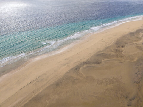 Aerial view of the ocean's turquoise embrace meeting the sandy beach, Jand&Atilde;&shy;a Natural Park, Fuerteventura, Canary Islands, Spain.
