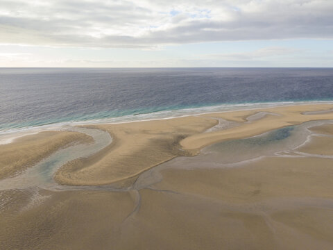Aerial view of the vast, rippled sand meeting the turquoise sea under a soft, cloudy sky, Jand&Atilde;&shy;a Natural Park, Fuerteventura, Canary Islands, Spain.