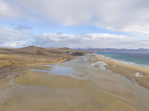 Aerial view of golden sands meeting turquoise waters under a vast sky, with dried peninsula due to the tide, Jand&Atilde;&shy;a Natural Park, Fuerteventura, Canary Islands, Spain.