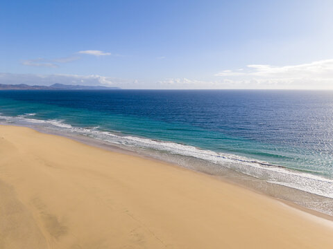 Aerial view of the shoreline where golden sands meet the turquoise sea under a clear blue sky, Jand&Atilde;&shy;a Natural Park, Fuerteventura, Canary Islands, Spain.