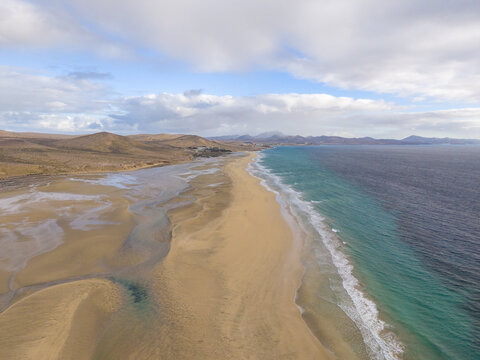 Aerial view of turquoise waters meet the golden sands of Jand&Atilde;&shy;a beachk under a sky of soft clouds, Jand&Atilde;&shy;a Natural Park, Fuerteventura, Canary Islands, Spain.
