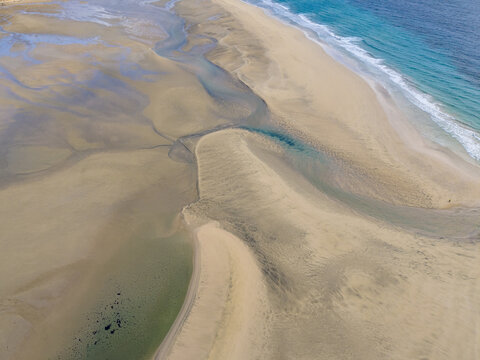 Aerial view of the rhythmic tidal patterns sculpting the golden sands where the turquoise ocean meets the shore, Jand&Atilde;&shy;a Natural Park, Fuerteventura, Canary Islands, Spain.